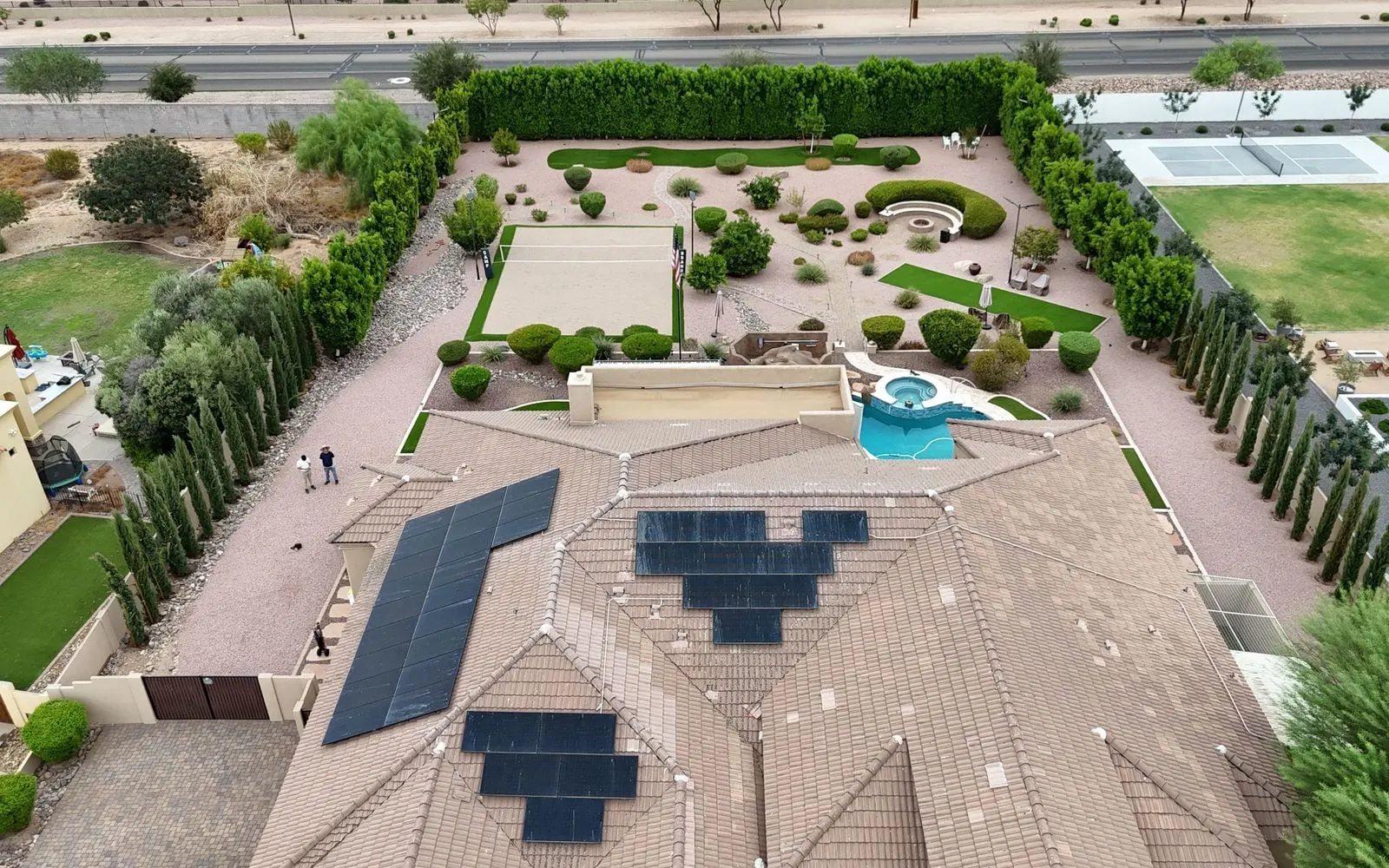 Drone view of a large desert home with several cleaned solar arrays on its tile roof