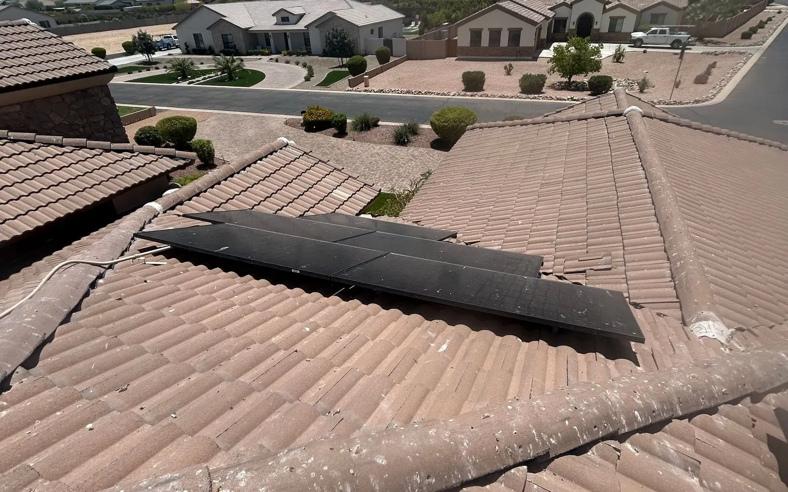 Before pigeon proofing: an open gap under rooftop solar panels with droppings on the tile ridge